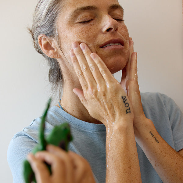 Person massaging More Than Nine skincare into their face