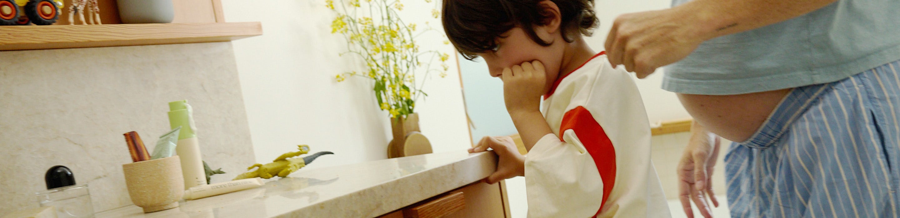 Mother applying skincare while a child sits beside her