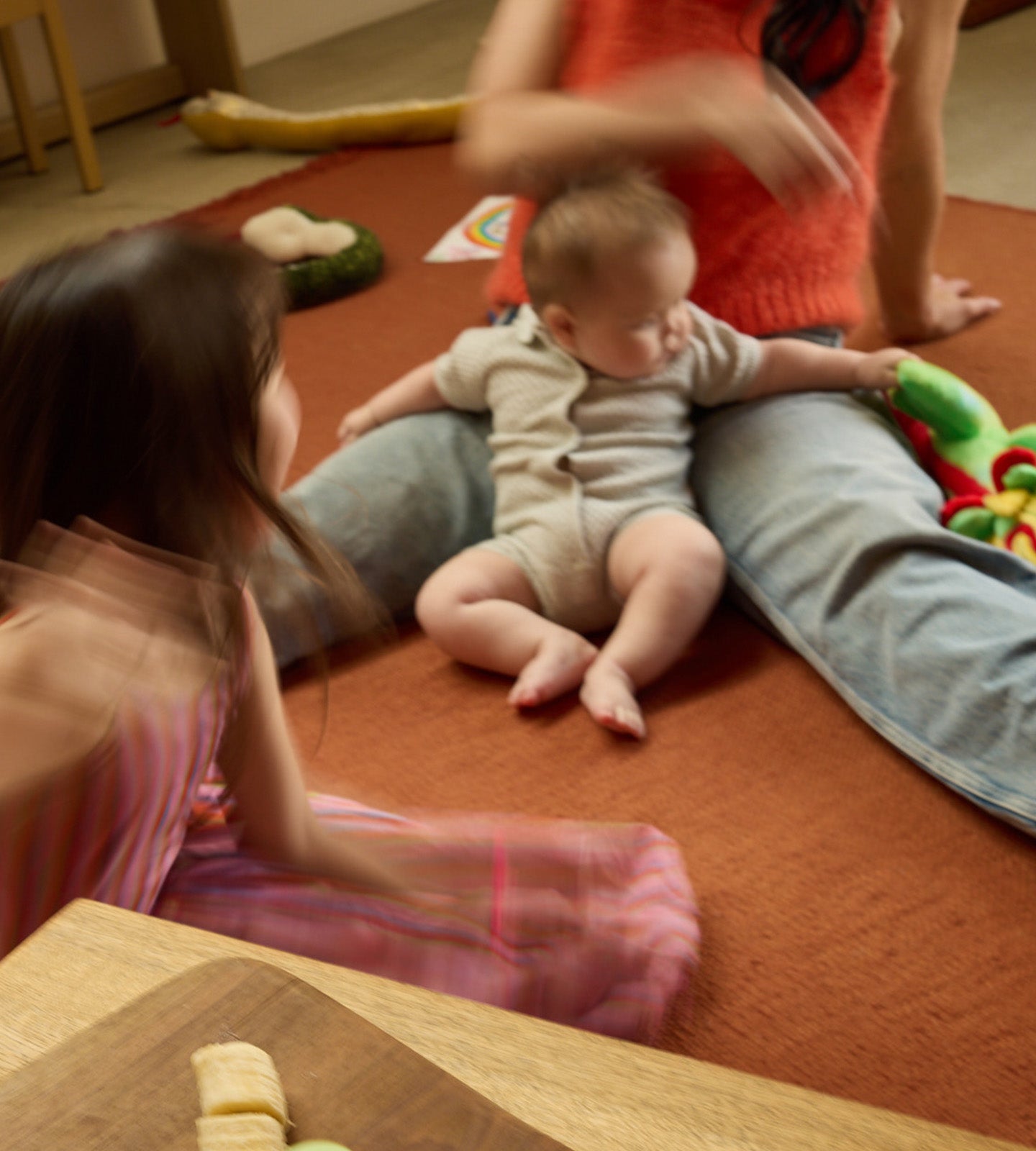 Parent and baby surrounded by children during a playroom moment