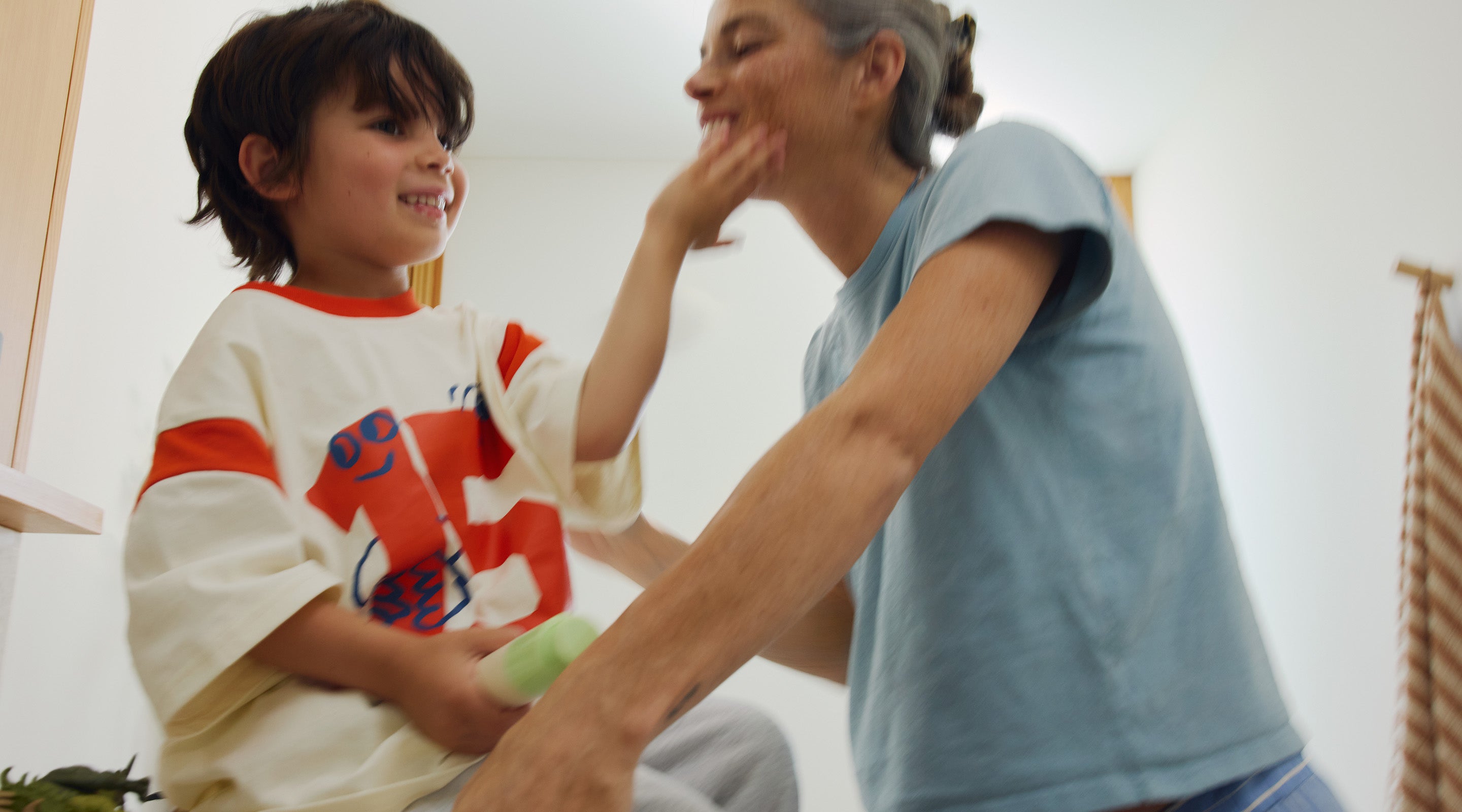 Mother applying skincare while a child sits beside her